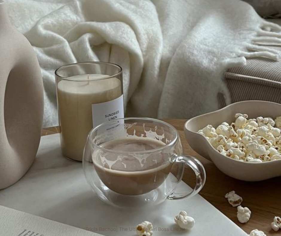 Cup of Cappuccino siting on a table next to popcorn , a candle and a cream blanket oozing an energy of I choose me